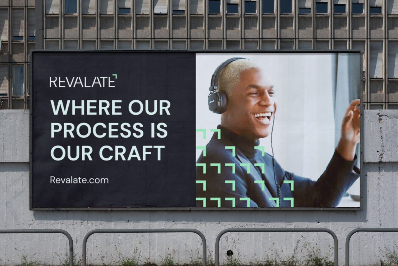 The billboard features the Revalate logo, proudly displaying the slogan Where Our Process Is Our Craft, alongside the website Revalate.com. A smiling person wearing headphones is set against dynamic geometric design elements, embodying Revalates innovative spirit.